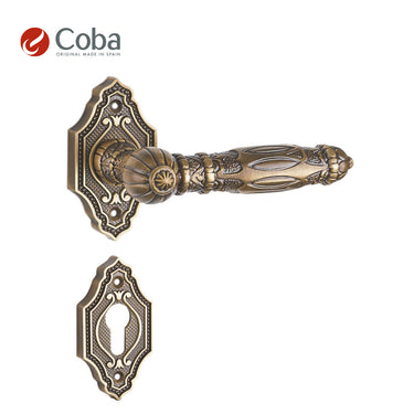 Bronces Coba 350-G Handle Set with Rosettes and Key Hole Escutcheon in Old Antique Brass Finish, made in Spain, featuring intricate vintage detailing.