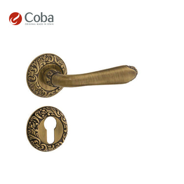 Bronces Coba 510-G Handle Set in Old Antique Brass Finish, made in Spain, featuring an intricate design with rosettes and key hole escutcheon.