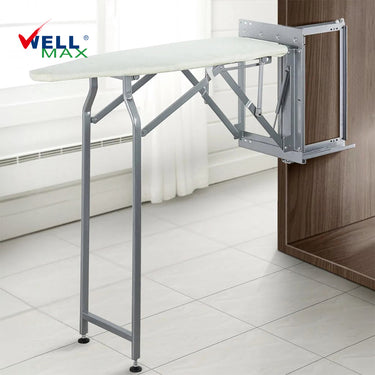 Referencing Folding Ironing Board HZ040C 3.jpg, the Wellmax folding ironing board is deployed from a dark wood wardrobe, showing its sturdy grey iron frame and supporting leg. Folding Ironing Board HZ040C 2.jpg displays the underside of the ironing board when folded up, highlighting the high-density through-hole network and structural reinforcement. Folding Ironing Board HZ040C 1.jpg shows a side profile of the folded ironing board, illustrating its compact, space-saving vertical position. Folding Ironing B