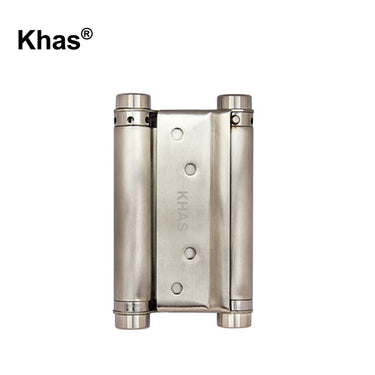 Khas double action hinge in a metallic finish, displaying its dual-cylinder spring mechanism for two-way door movement and Khas engraving.