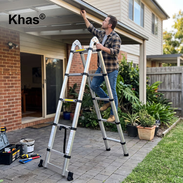 Referencing image 52, the Khas aluminum two-way telescopic ladder stands independently in its A-frame configuration against a white background. Image 53 provides detailed close-up callouts highlighting the ladder's hinge and release rod, slip-resistant rung, slide latch, stabilizer bar, and non-slip bottom cap. Image 54 shows a man standing on the ladder outdoors on a patio, using its sturdy A-frame setup to reach and inspect the roof trim.