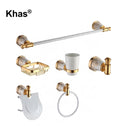 Referencing White and Gold Marble Type Bathroom Accessories Set 1.jpg, the complete Khas bathroom set—including a towel bar, soap dish, tumbler holder, robe hook, toilet paper holder, and towel ring—is displayed against a pristine white background, highlighting the white and gold marble finish. White and Gold Marble Type Bathroom Accessories Set 2.jpg shows the luxurious hardware fully installed in a warm, tiled bathroom setting, actively holding a towel, soap, and toothbrushes. White and Gold Marble Type B