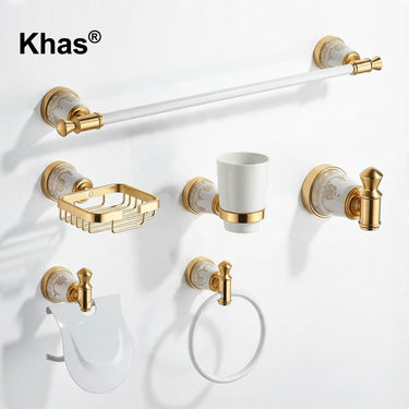 Referencing White and Gold Marble Type Bathroom Accessories Set 1.jpg, the complete Khas bathroom set—including a towel bar, soap dish, tumbler holder, robe hook, toilet paper holder, and towel ring—is displayed against a pristine white background, highlighting the white and gold marble finish. White and Gold Marble Type Bathroom Accessories Set 2.jpg shows the luxurious hardware fully installed in a warm, tiled bathroom setting, actively holding a towel, soap, and toothbrushes. White and Gold Marble Type B