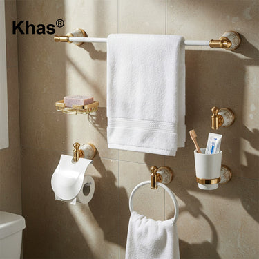 Referencing White and Gold Marble Type Bathroom Accessories Set 1.jpg, the complete Khas bathroom set—including a towel bar, soap dish, tumbler holder, robe hook, toilet paper holder, and towel ring—is displayed against a pristine white background, highlighting the white and gold marble finish. White and Gold Marble Type Bathroom Accessories Set 2.jpg shows the luxurious hardware fully installed in a warm, tiled bathroom setting, actively holding a towel, soap, and toothbrushes. White and Gold Marble Type B